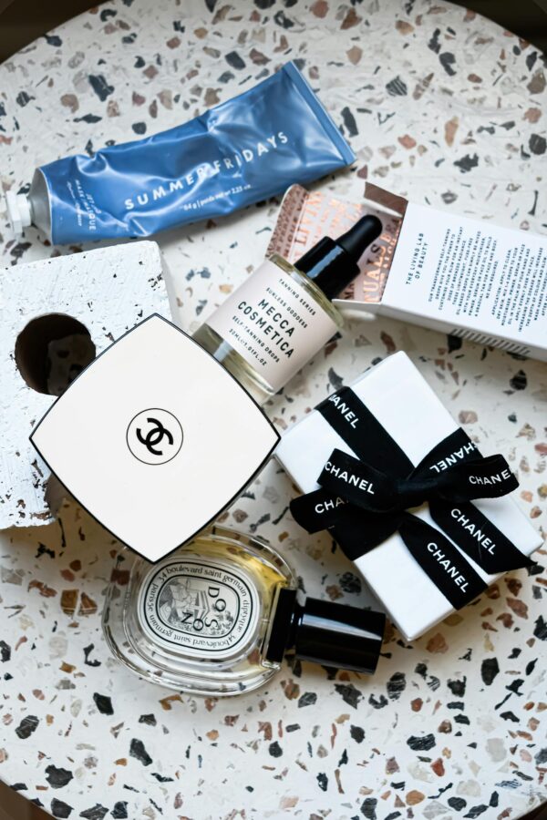 A stylish flat lay of high-end cosmetic products including Chanel packaging on a textured surface.
