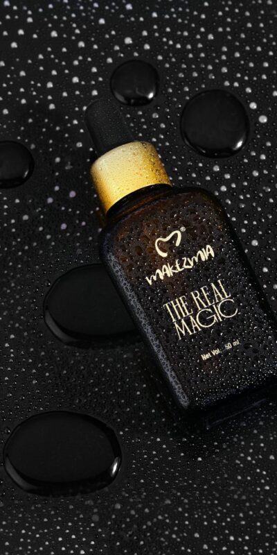 High-end black cosmetic bottle with water droplets, showcasing elegance and freshness.