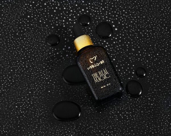 High-end black cosmetic bottle with water droplets, showcasing elegance and freshness.